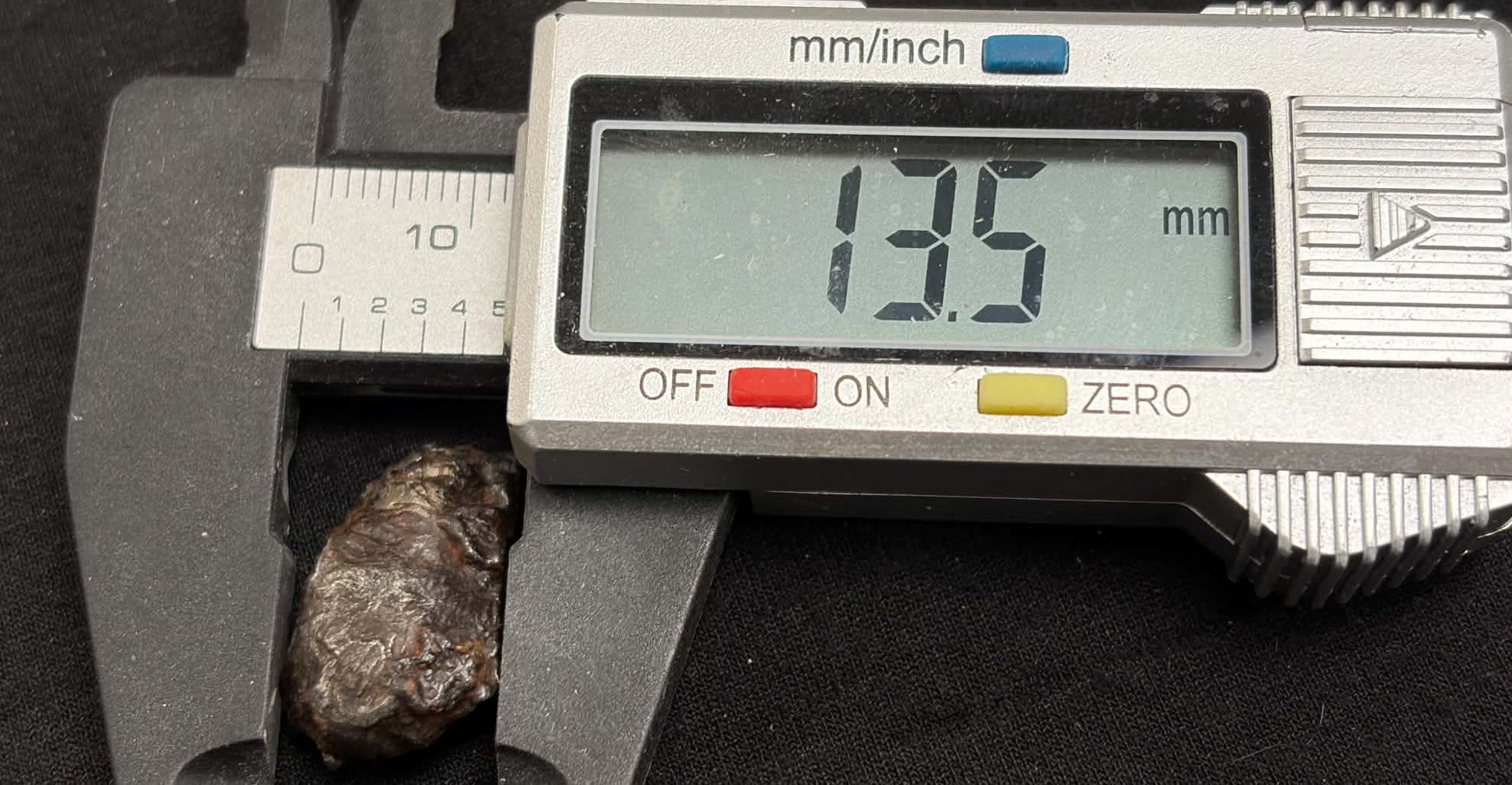 Sikhote-Alin meteorite caliper measurement — width approx. 13.5mm