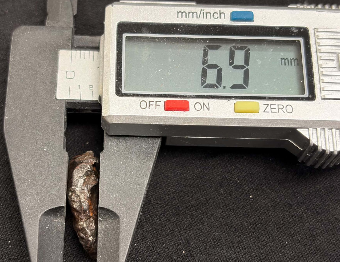Sikhote-Alin meteorite caliper measurement — depth approx. 6.9mm